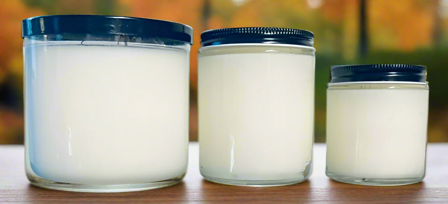 Three glass jars with black lids on a table, with a blurred background.