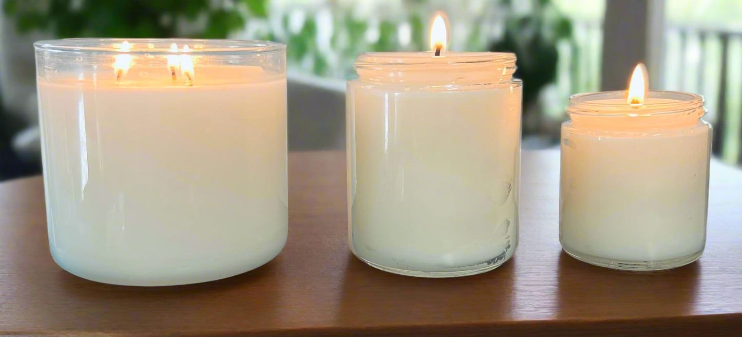 Three white candles of different sizes on a dark surface with a light gray background