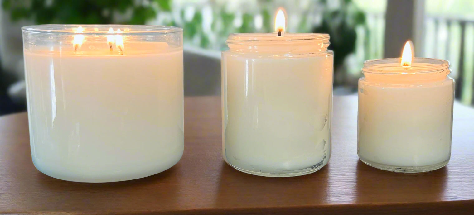 Three white candles of different sizes on a dark surface with a light gray background